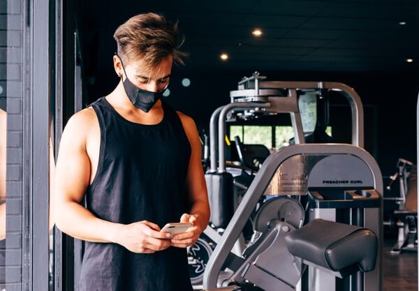 young-man-wearing-face-mask-looks-his-smartphone-gym_244940-108